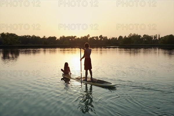 Caucasian boy and girl on paddleboard on lake