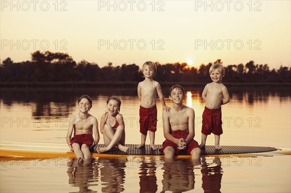 Caucasian children sitting on paddleboard