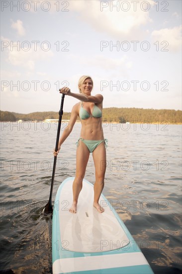 Caucasian woman on paddleboard on lake