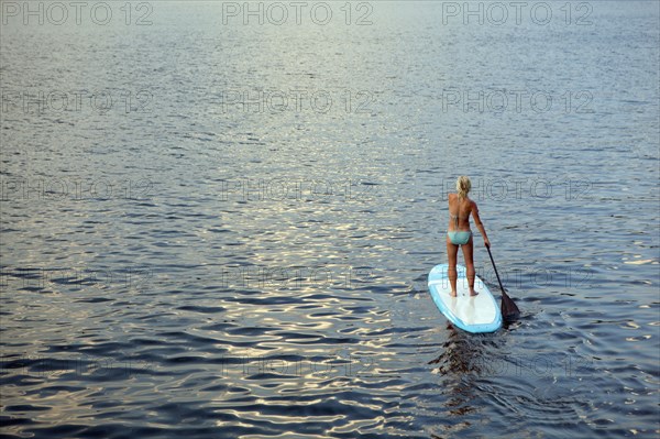 Caucasian woman on paddleboard on lake