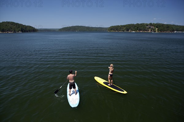 Caucasian couple on paddle boards on lake