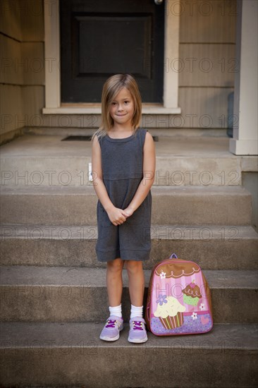 Caucasian girl with backpack on front steps