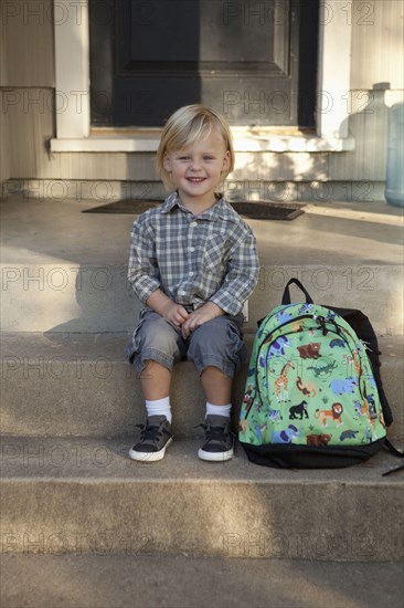 Caucasian boy with backpack on front steps