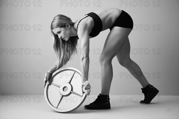Caucasian woman lifting weight disc