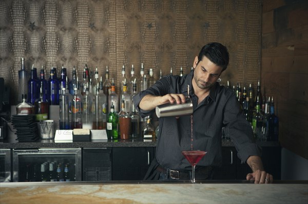 Caucasian bartender pouring drinks at bar