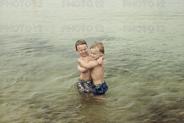 Caucasian boys hugging in lake
