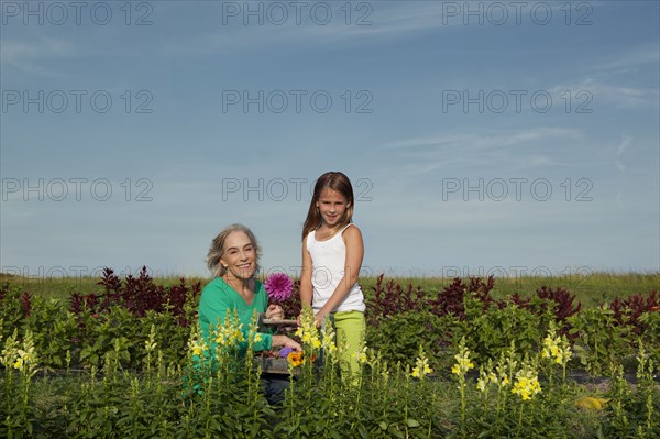 Caucasian grandmother and granddaughter picking flowers on farm