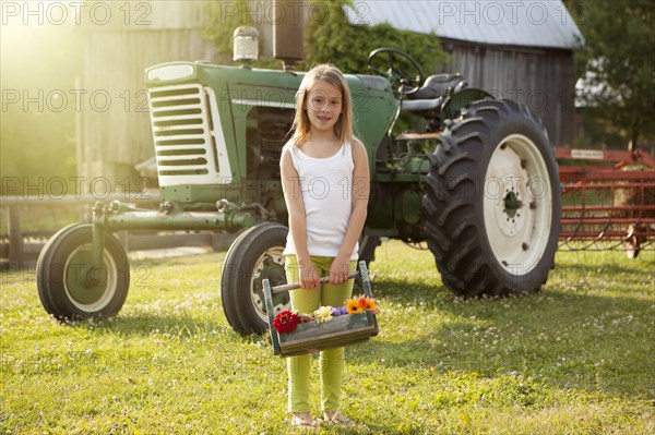 Caucasian girl holding basket of flowers on farm