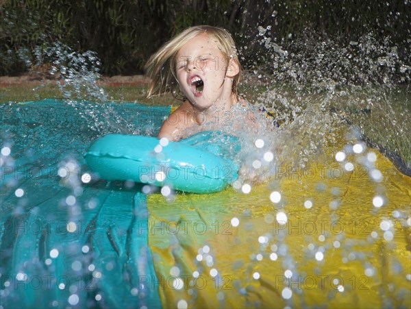 Caucasian boy playing on water slide