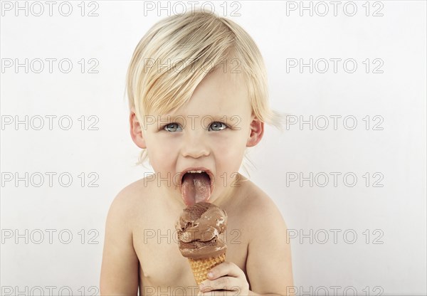 Caucasian boy licking chocolate ice cream cone