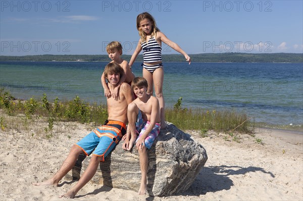 Caucasian cousins standing on rock at beach