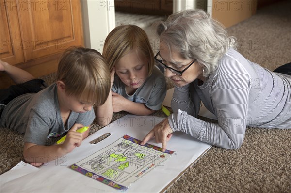 Caucasian grandmother and grandchildren coloring together on floor