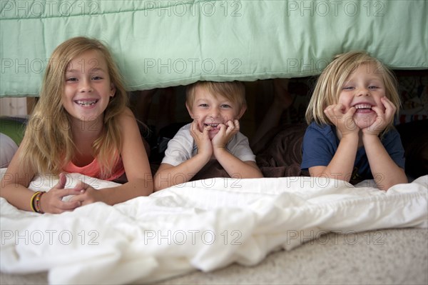 Caucasian children laying under bed