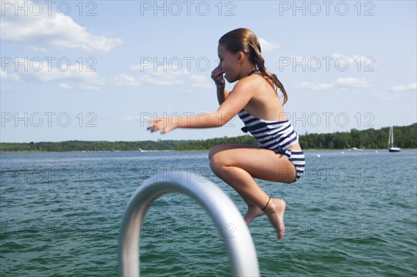 Caucasian girl jumping into lake