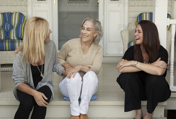 Caucasian mother and daughters smiling on front porch