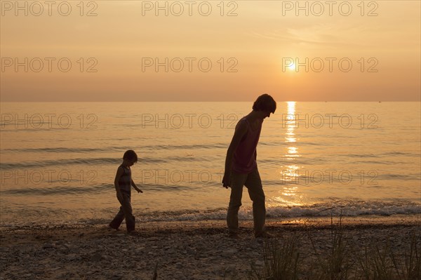 Caucasian brothers walking on beach at sunset