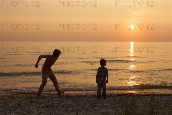 Caucasian brothers playing on beach at sunset