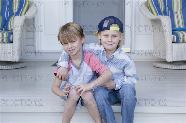 Caucasian boys hugging on porch