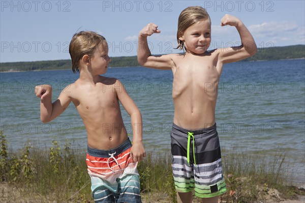 Caucasian boys flexing muscles on beach