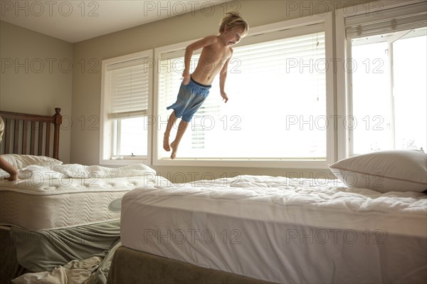 Caucasian boy jumping on bed