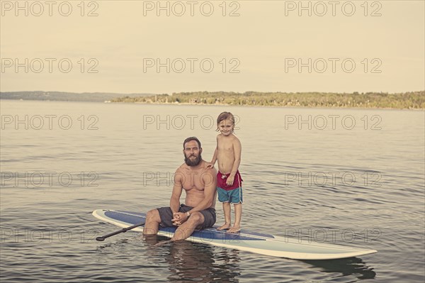 Caucasian father and son on paddleboard in lake