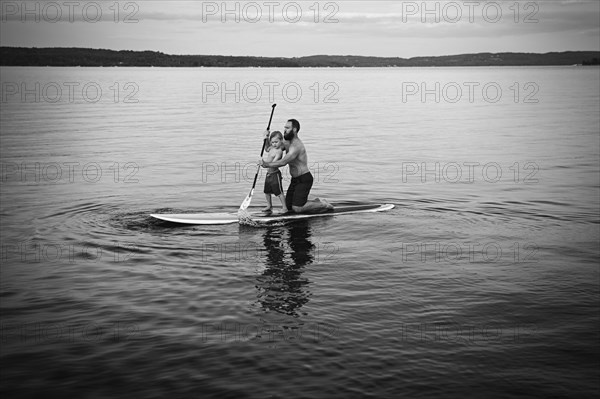 Caucasian father and son on paddleboard in lake