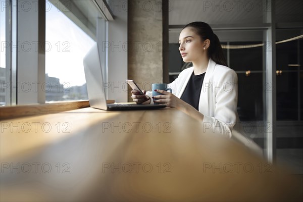 Caucasian woman drinking coffee and texting on cell phone