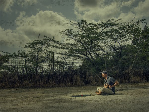 Caucasian man fishing in arid puddle