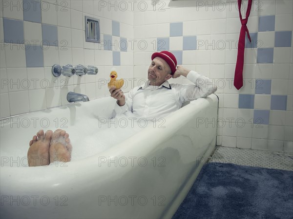 Caucasian businessman wearing clothing in bathtub