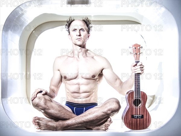 Caucasian musician holding ukulele in small alcove