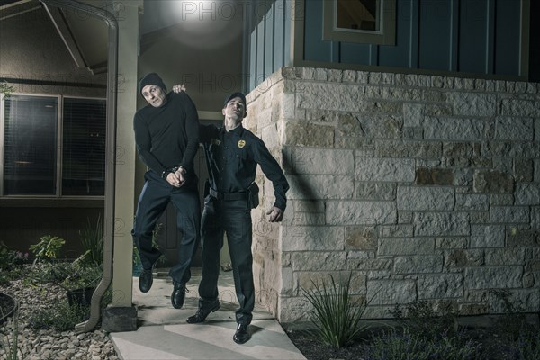 Caucasian police lifting burglar in handcuffs