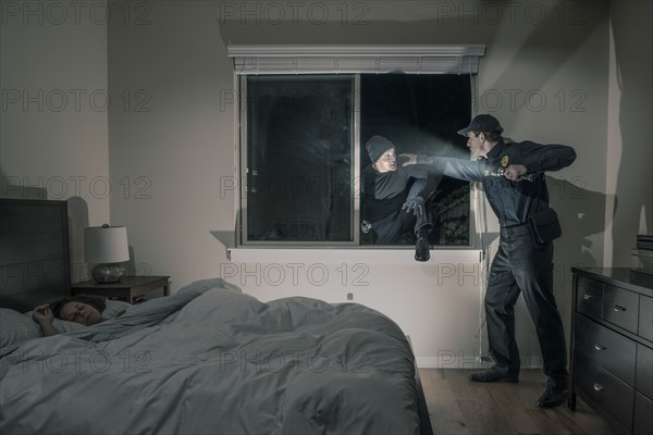 Caucasian police officer shining flashlight on house burglar