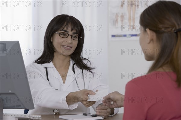 Female doctor handing prescription to patient