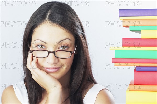 Woman wearing eyeglasses next to stack of books