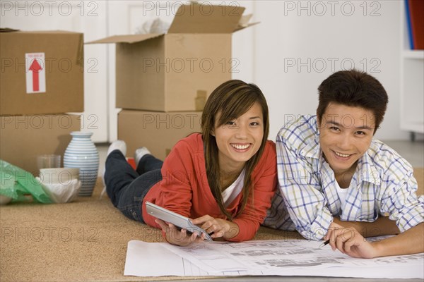 Asian couple looking at blueprints in new house