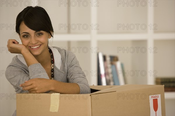 Young woman leaning on moving box