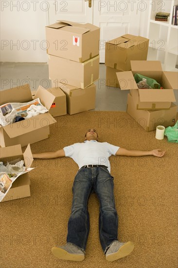 Man laying on floor next to moving boxes