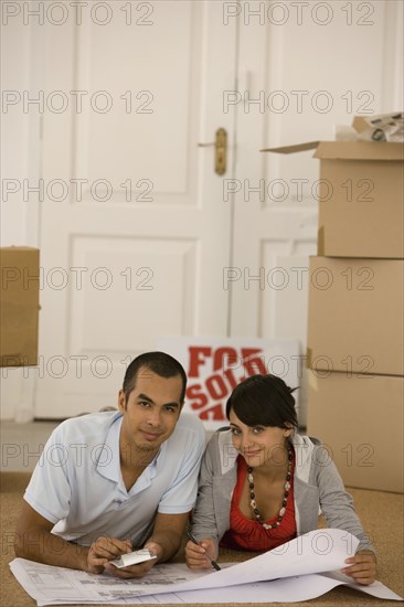 Young couple looking at blueprints in new house