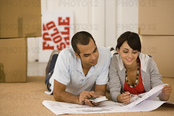 Young couple looking at blueprints in new house