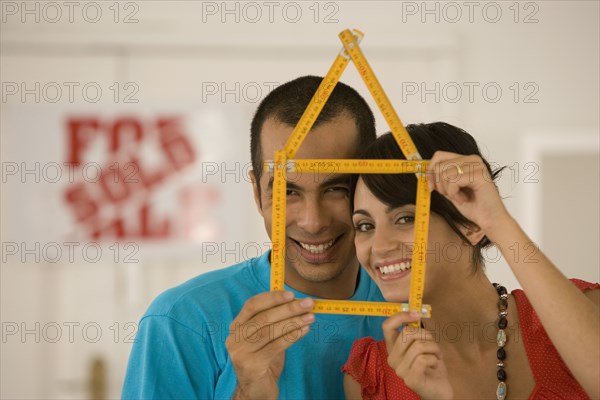 Couple holding folding ruler shaped like house