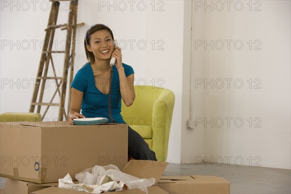 Asian woman talking on telephone in new house