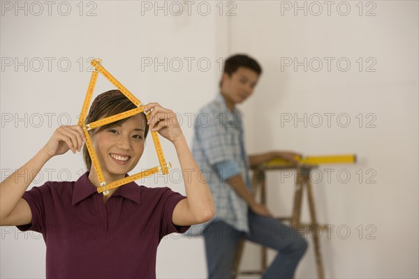 Asian woman with folding ruler shaped like house