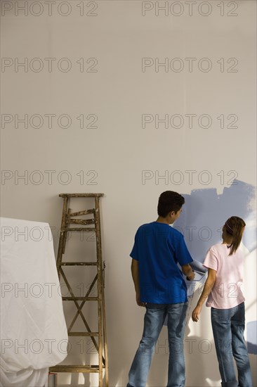 Asian couple painting interior of house