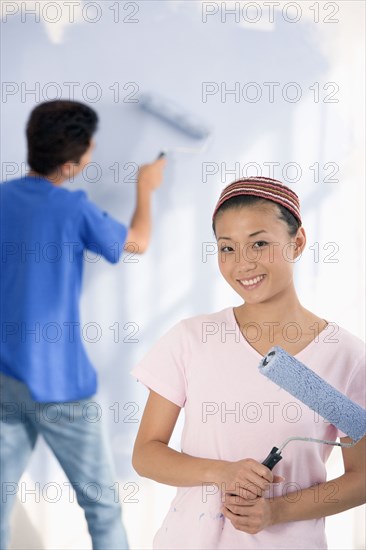 Asian couple painting interior of house