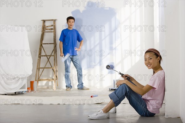 Asian couple painting interior of house