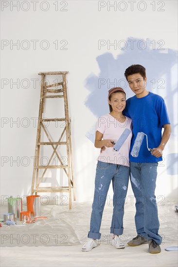 Asian couple painting interior of house