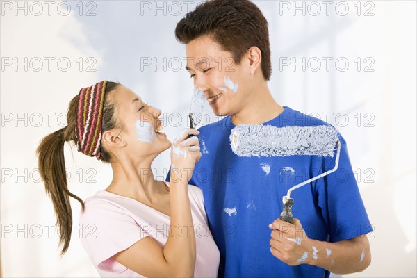 Asian couple painting and being playful