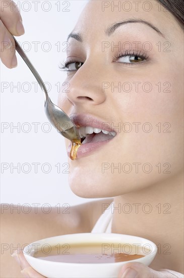 Mixed Race woman dripping honey on lips