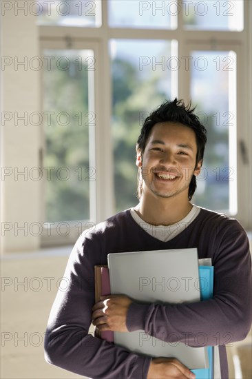 Asian man holding binders