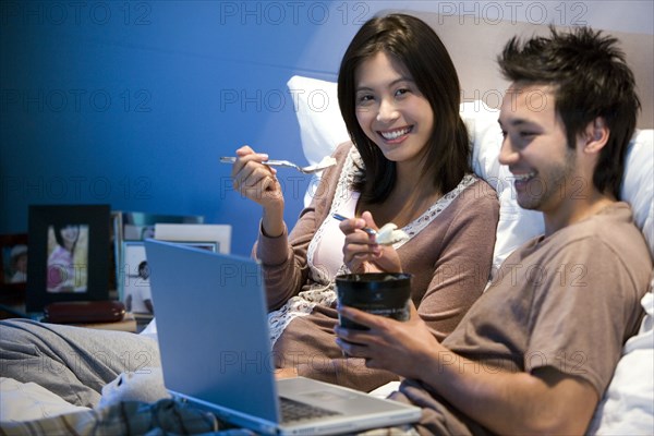 Asian couple eating ice cream in bed